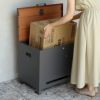 ダークグレーの宅配ボックスの設置イメージ。ワンピースを着た人が宅配ボックスから段ボールの荷物を取り出している。
