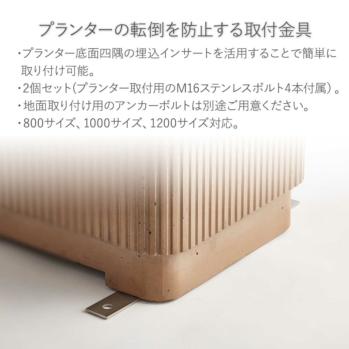 使用例の画像。プランターの転倒を防止する取付金具です。プランター底面四隅の埋込インサートを活用することで簡単に取り付け可能です。2個セット（プランター取付用のM16ステンレスボルト4本付属）。地面取り付け用のアンカーボルトは別途ご用意ください。800サイズ、1000サイズ、1200サイズ対応しています。