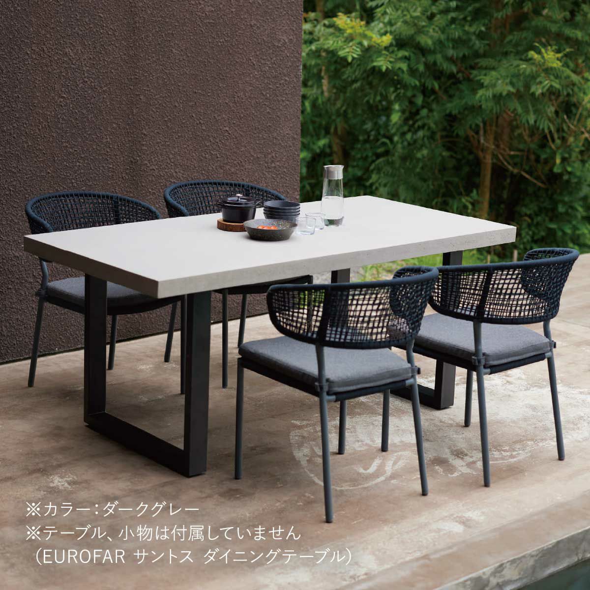 屋外のデッキにホワイトのダイニングテーブルとダークグレーのチェアが置いてある画像です。テーブル、小物は付属していません（EUROFAR サントス ダイニングテーブル）