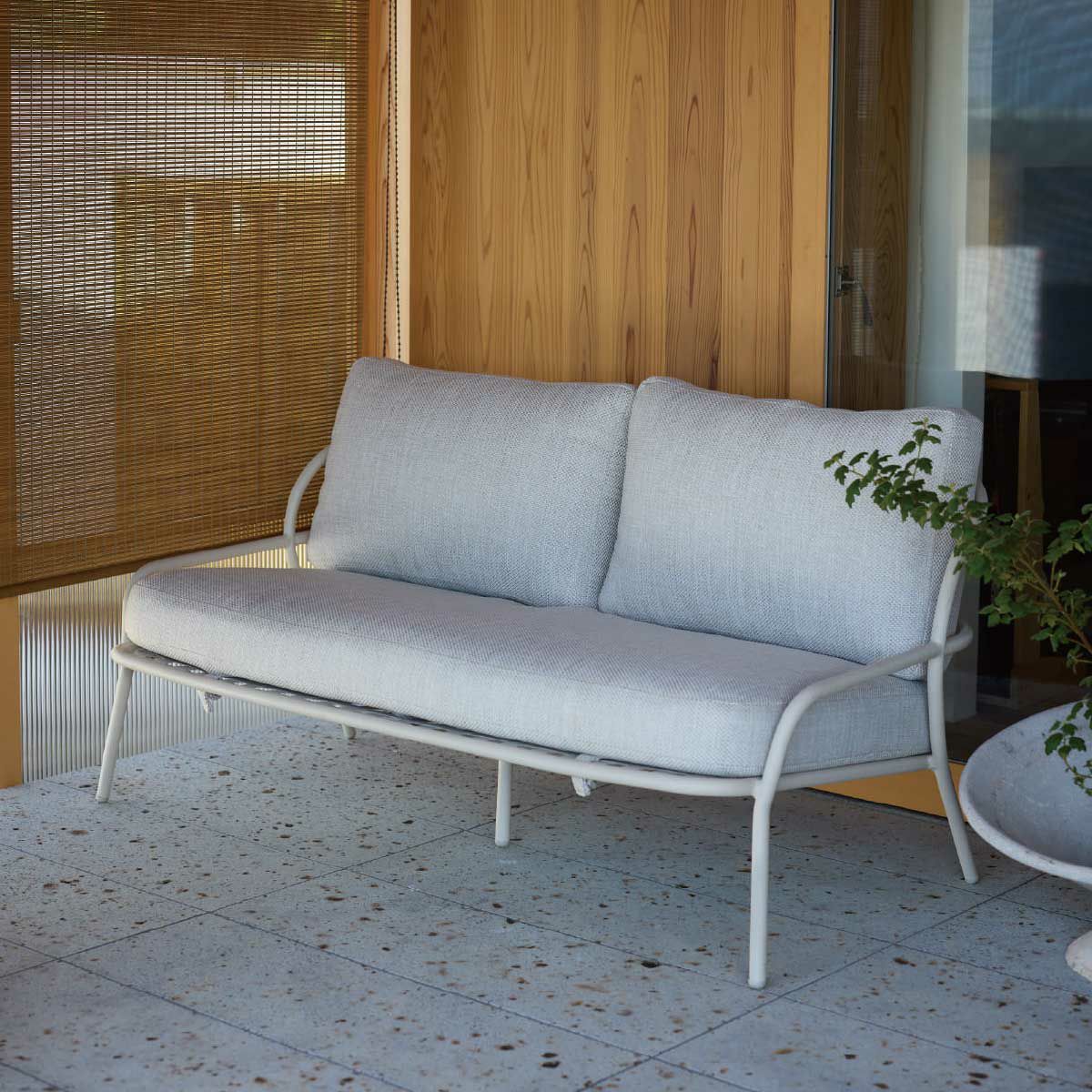 屋外の白いタイルのデッキにホワイトのダブルソファとサイドテーブルが置かれている画像です。※テーブルは付属していません
