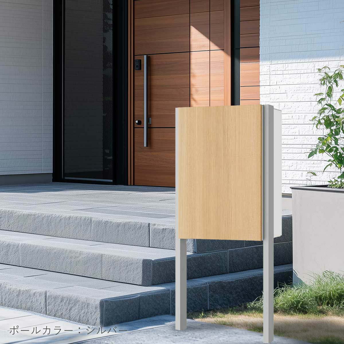 ナスタボックスプラスポストの設置イメージ。住宅の玄関ポーチ横に設置されている。宅配ボックスのカラーは木目調のアッシュ、ポールのカラーはシルバー。