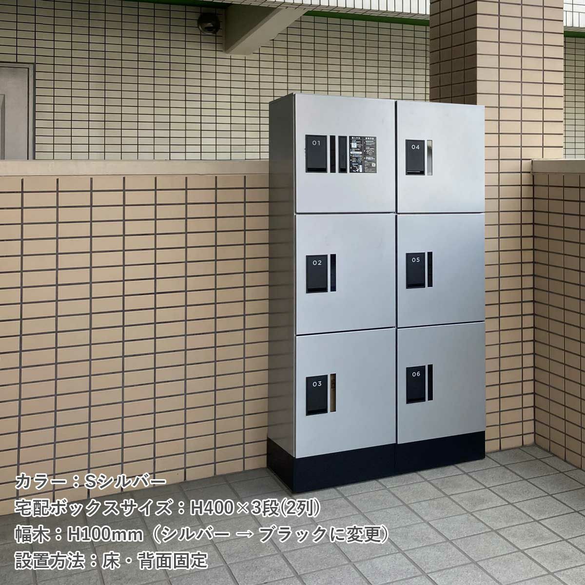 アパートの前に宅配ボックスが設置されている。宅配ボックスのカラーはSシルバー。宅配ボックスのサイズH400×3段（2列）。幅木はシルバーからブラックに変更。設置方法は床・背面固定タイプ。